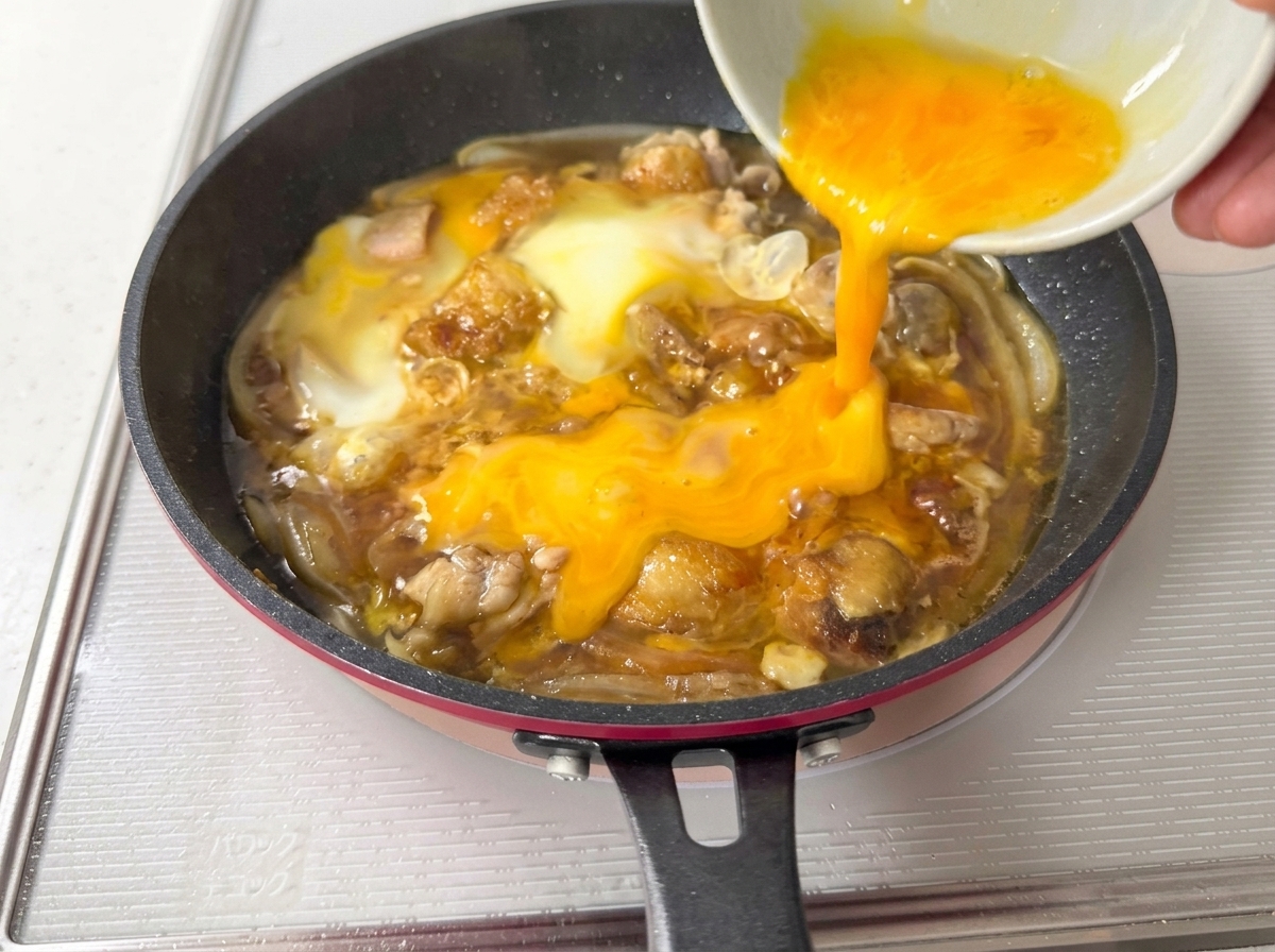 Le uova sbattute rimanenti versate nella padella, coprendo gli ingredienti parzialmente cotti.
