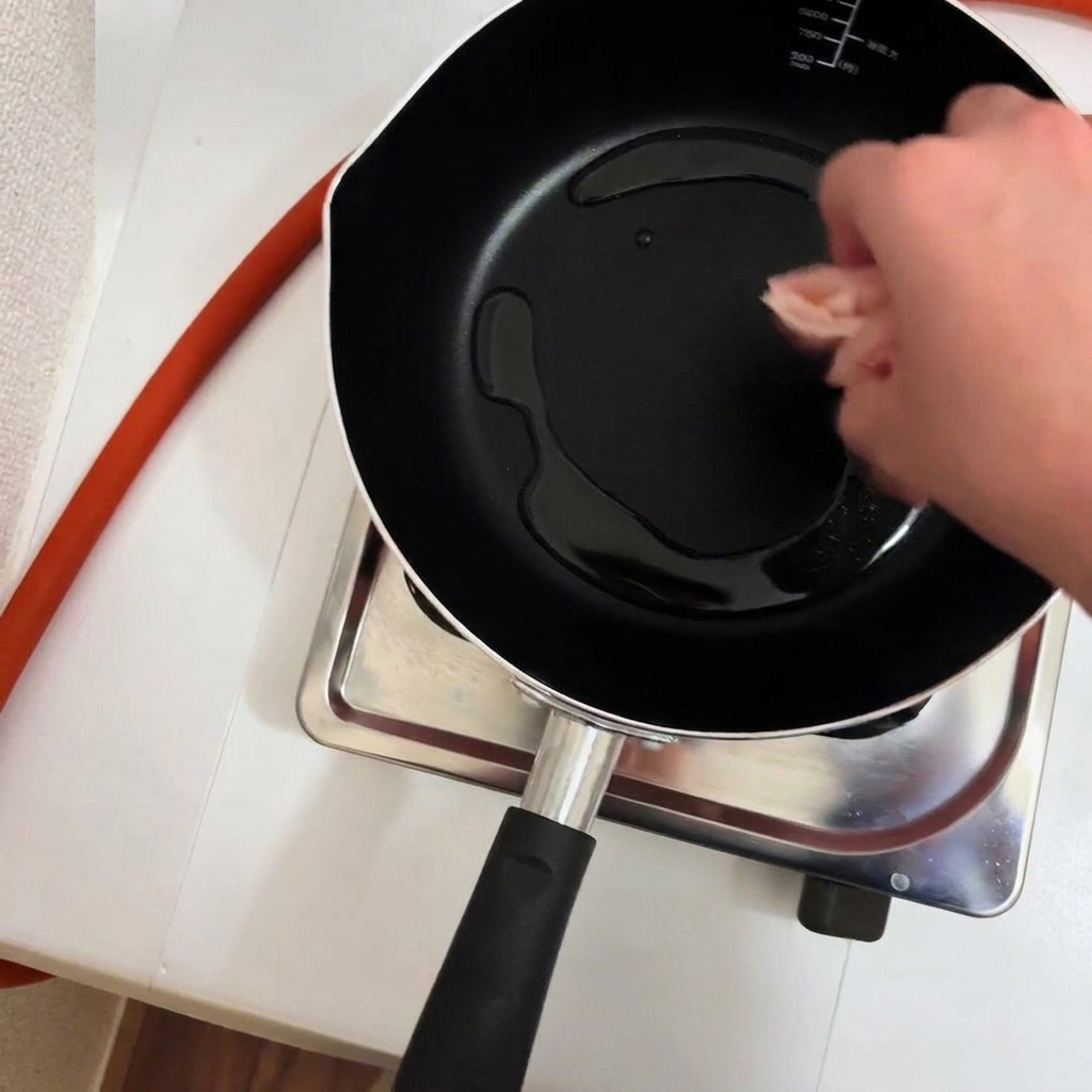 Pezzi di pollo in una padella con olio caldo.