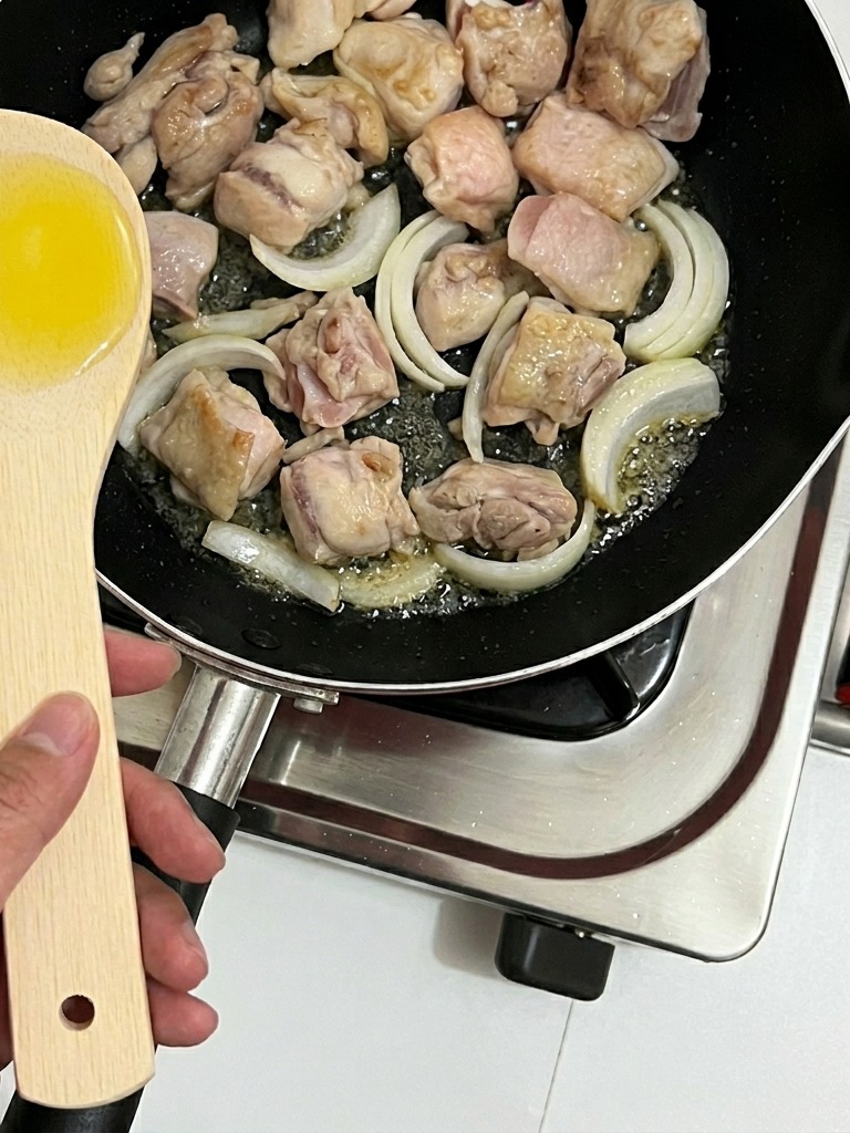 Strisce di cipolla mescolate al pollo in padella.