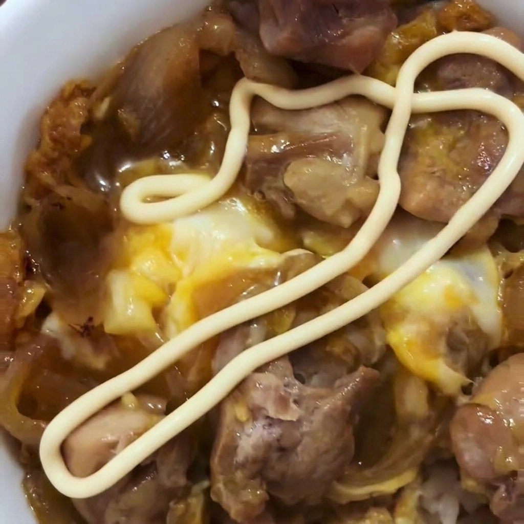 Uova sbattute versate sopra il pollo e le cipolle in una padella.
