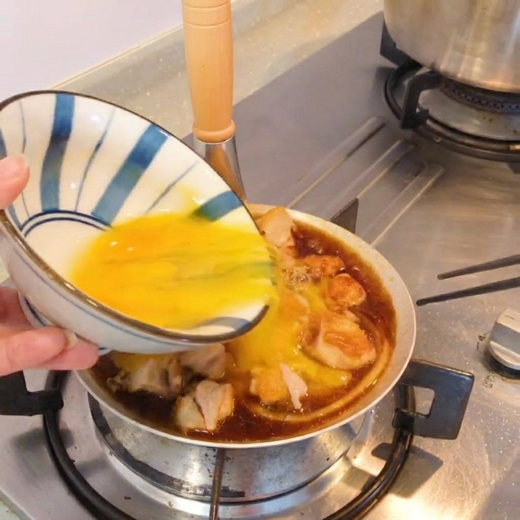 Un piatto finito in stile Oyakodon nella padella, guarnito con cipollotto fresco.