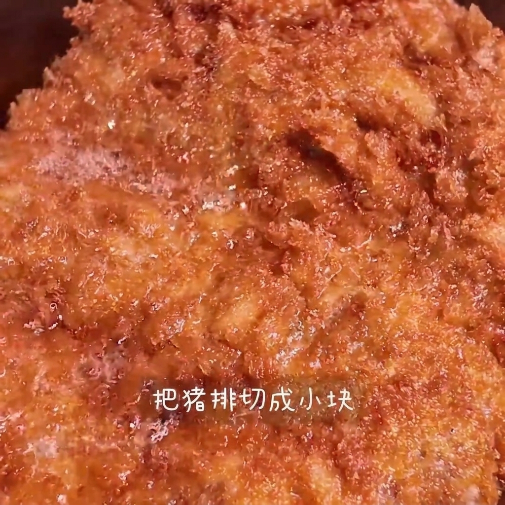 Una cotoletta fritta dorata che viene tagliata a strisce su un tagliere di legno.