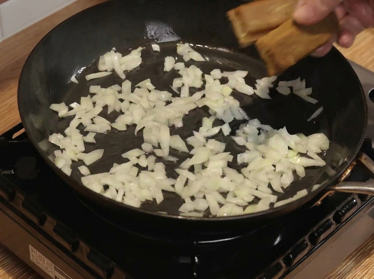 Dadi di curry e acqua mescolati con cipolle saltate in padella.