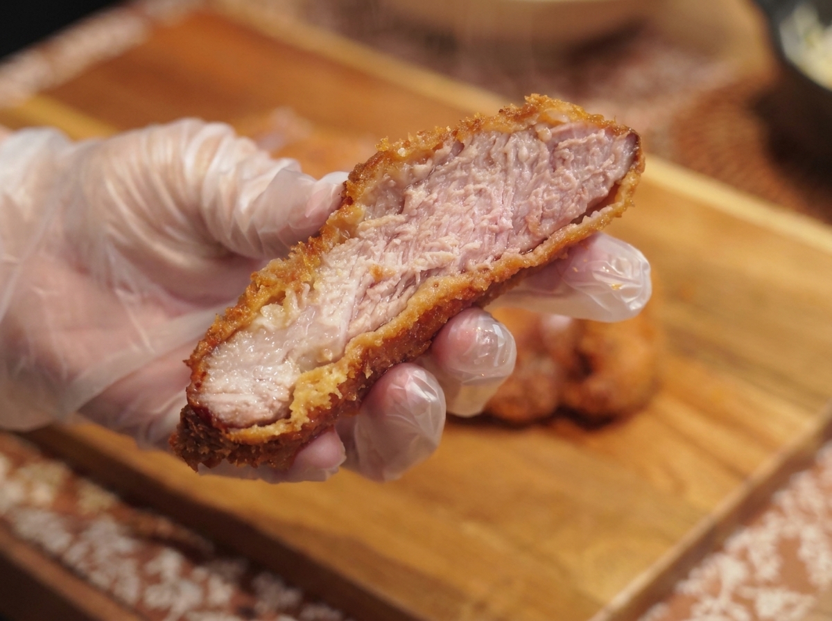 Una ciotola completa di riso al curry sormontata da uova strapazzate, cotoletta a fette e prezzemolo.