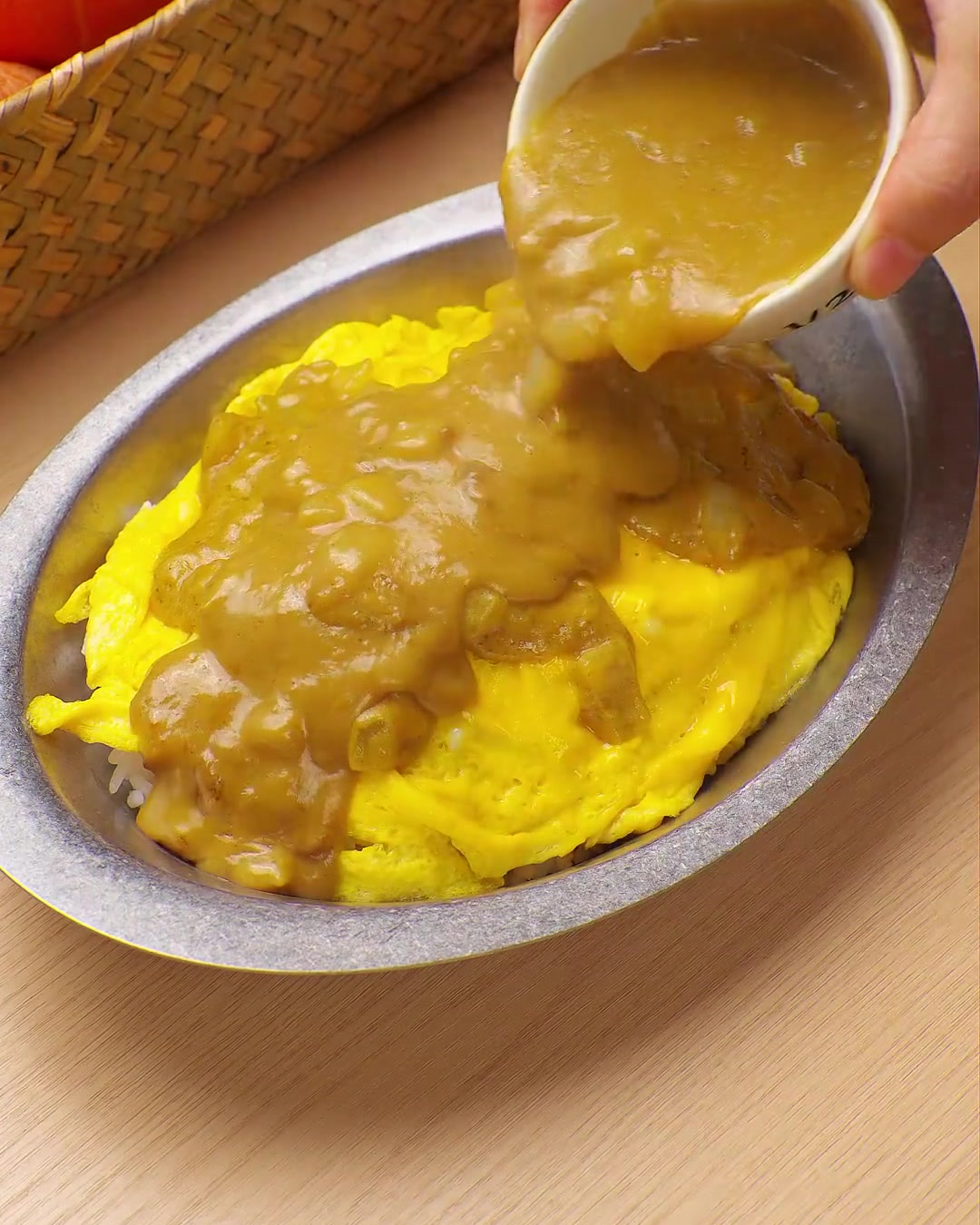 Una ricca salsa al curry gialla versata da una ciotolina su un letto di uova strapazzate e riso.