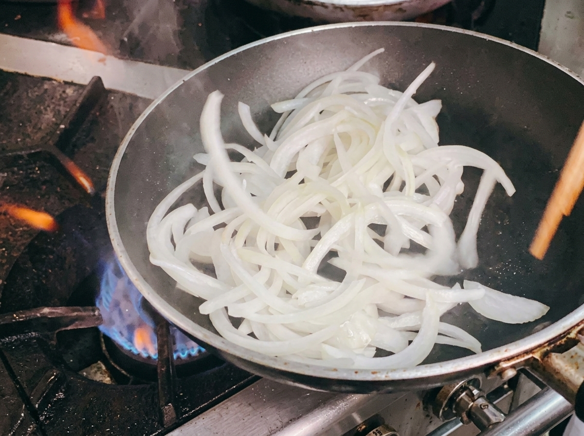 Soffriggere le cipolle affettate in padella con bacchette.