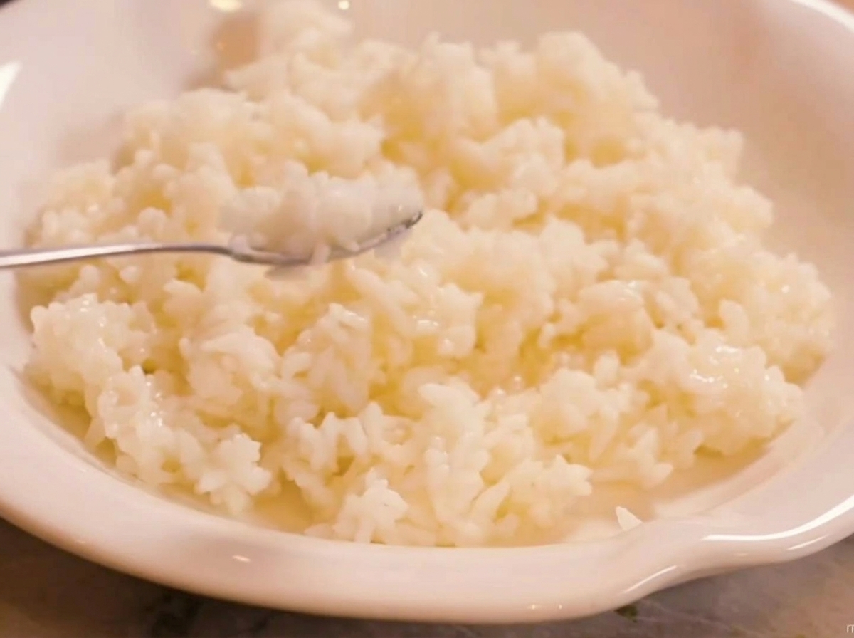 Riso profumato thailandese cotto al vapore combinato con aceto di riso in una ciotola bianca, mostrando la consistenza e il colore del riso condito.