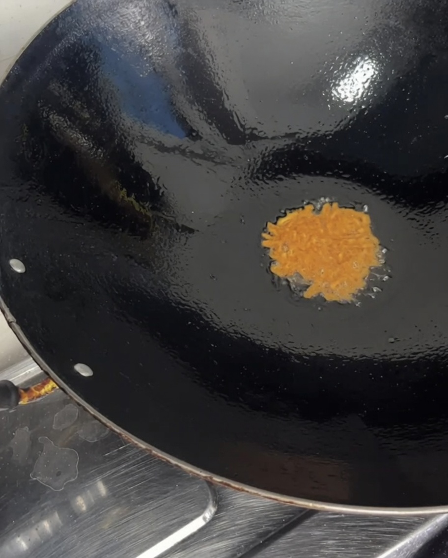 Ricci di mare arancioni versati da una ciotola in un wok caldo.