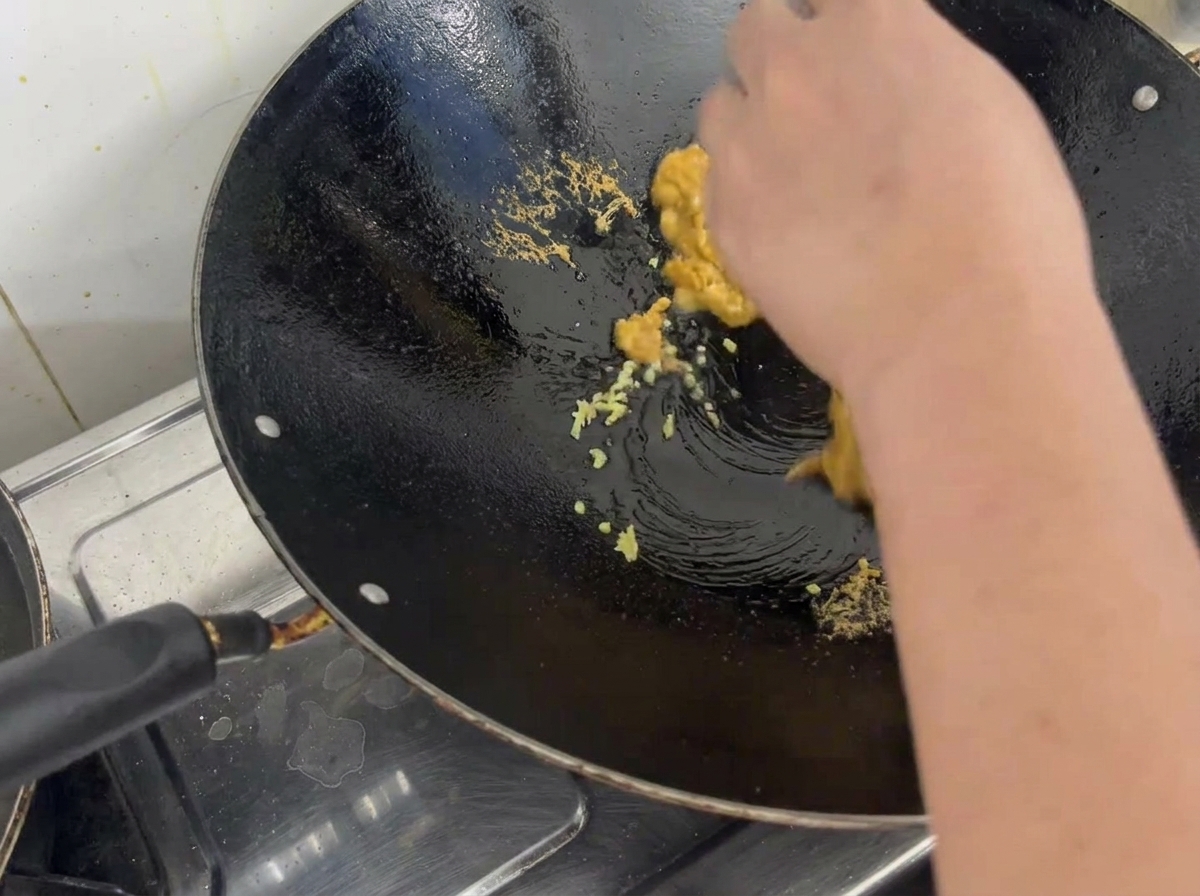 Ricci di mare cotti sbriciolati con zenzero in un wok di metallo.