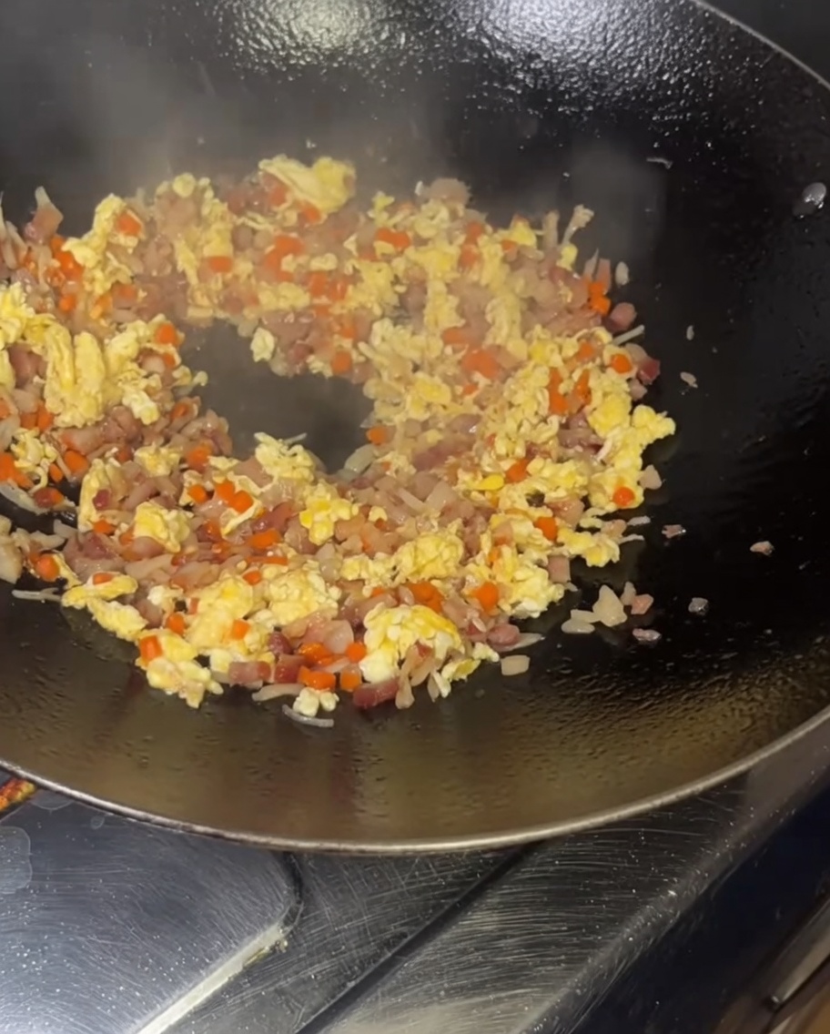 Versare il riso alluovo in un wok fumante.