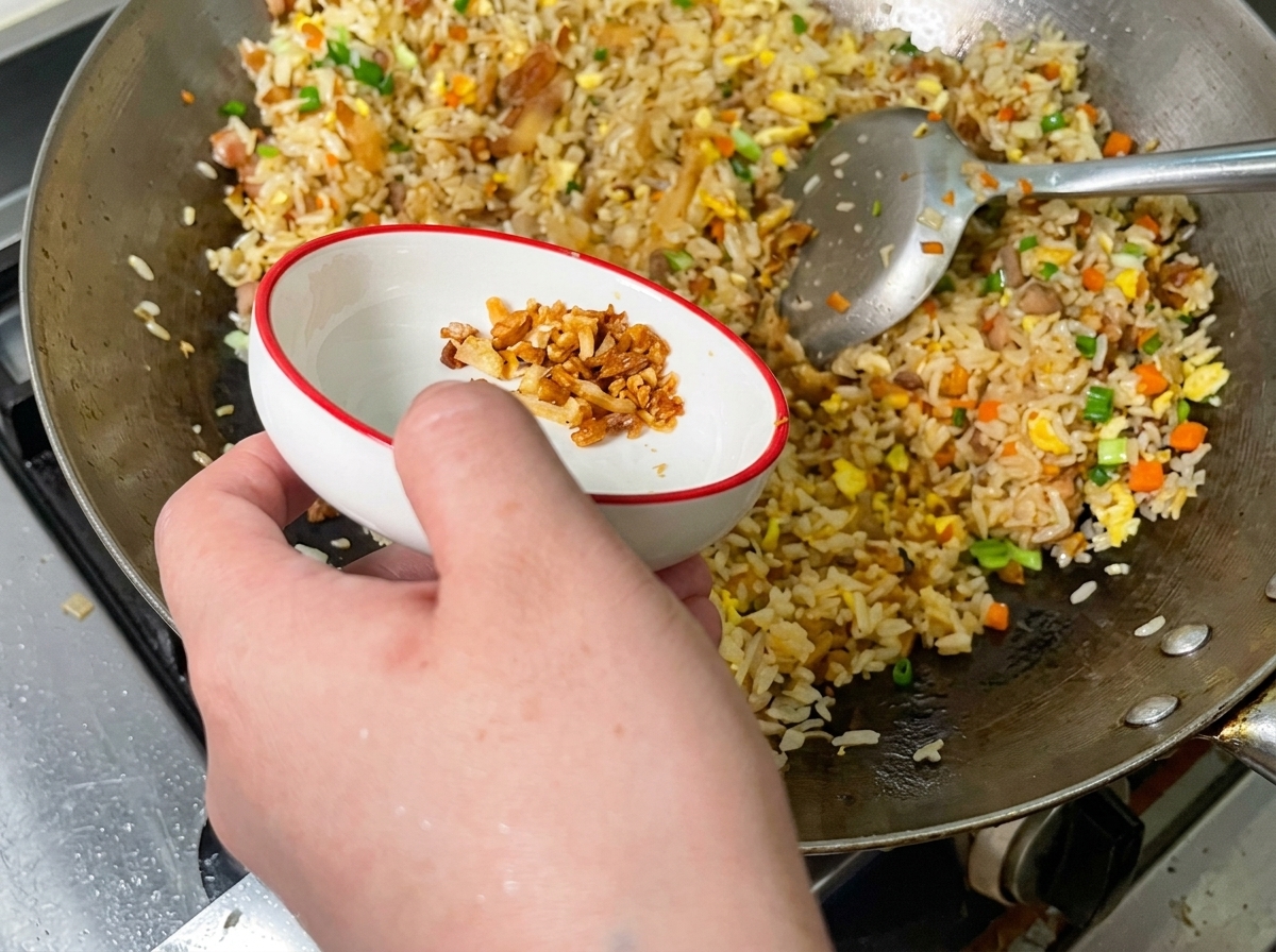 Ciccioli di maiale croccanti sparsi sul riso nel wok.
