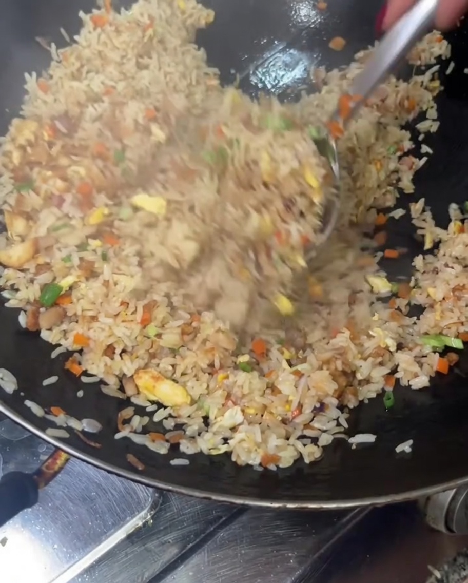 Riso saltato che viene mescolato unultima volta in un wok grande.