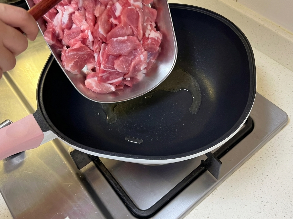 Maiale tagliato a fette sottili aggiunto in una padella calda con olio sfrigolante.