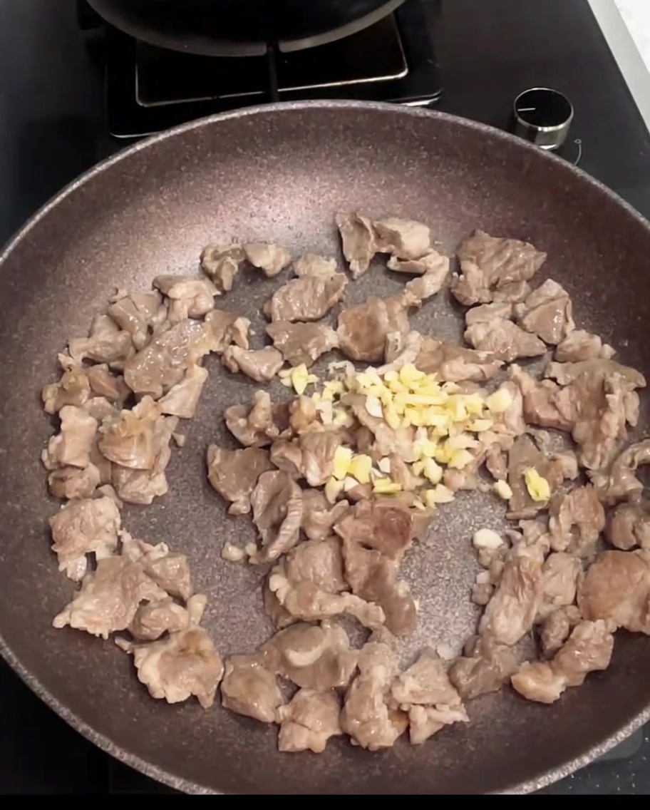 Pezzi di maiale saltati in padella con aglio tritato appena aggiunto.