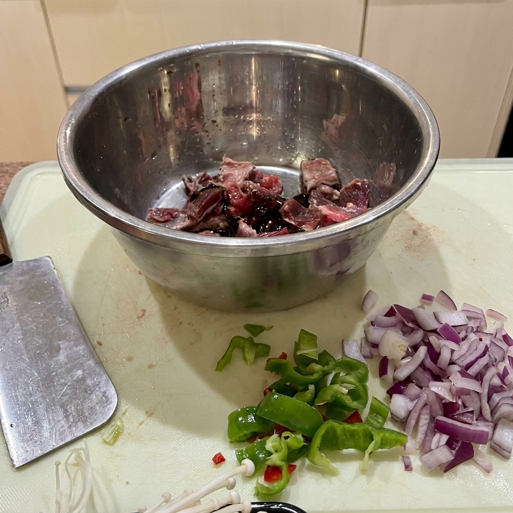 Pezzi di manzo in una ciotola di acciaio inox, marinati con salsa di soia, salsa di ostriche e fecola.