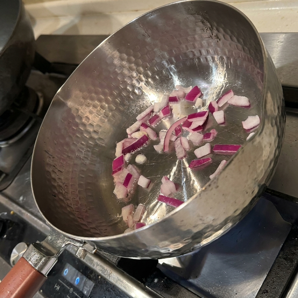 Cubetti di cipolla che sfrigolano in una padella calda con olio, diventando fragranti e morbidi.