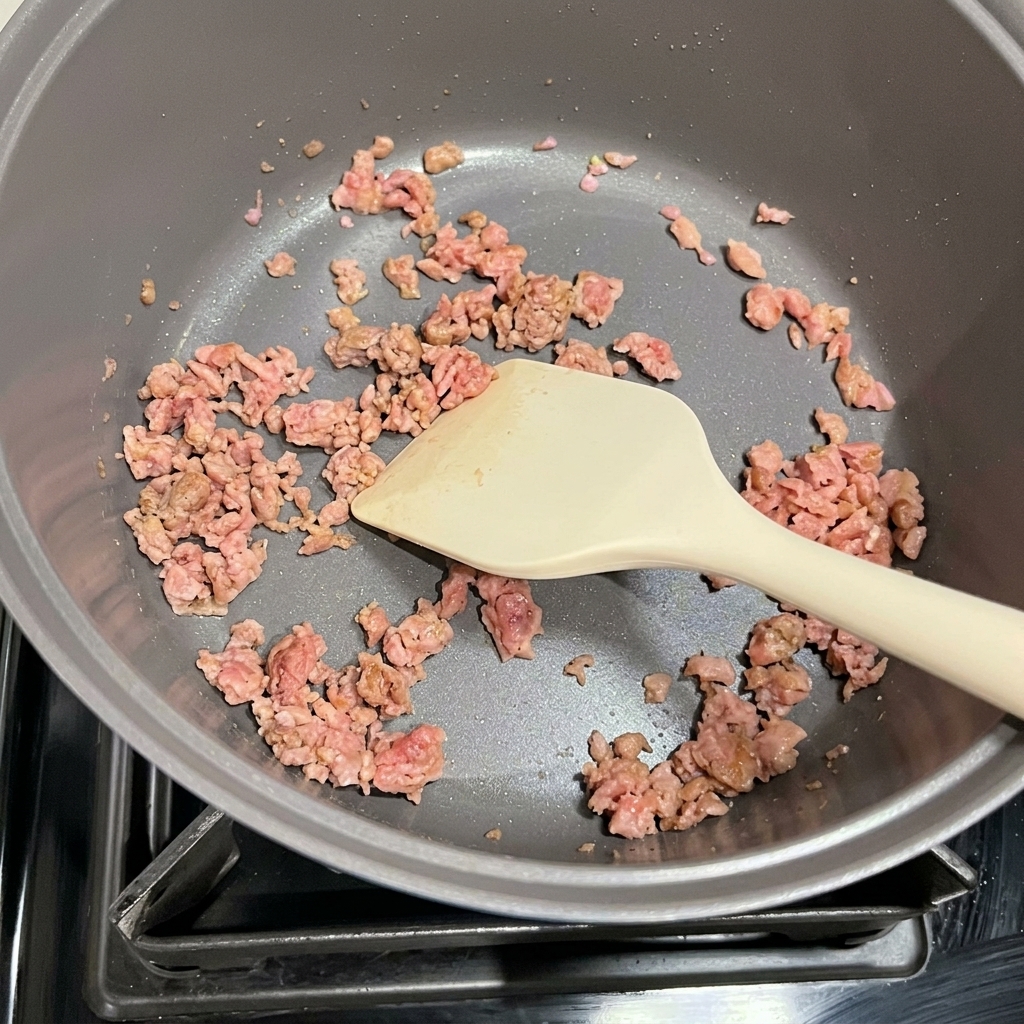 Kimchi e Spam rosolato mentre vengono soffritti insieme in una pentola.