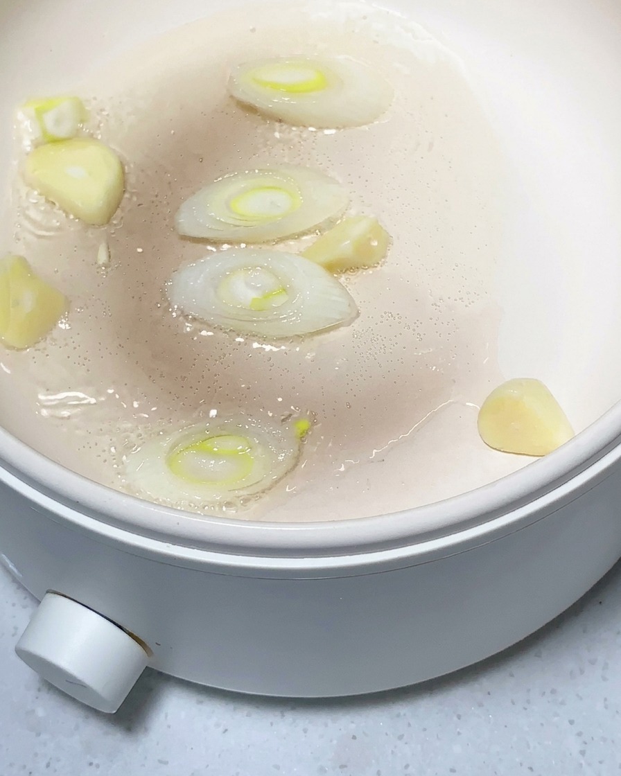 Pezzi di patata, aglio tritato e zenzero soffritti in una padella leggermente oliata.
