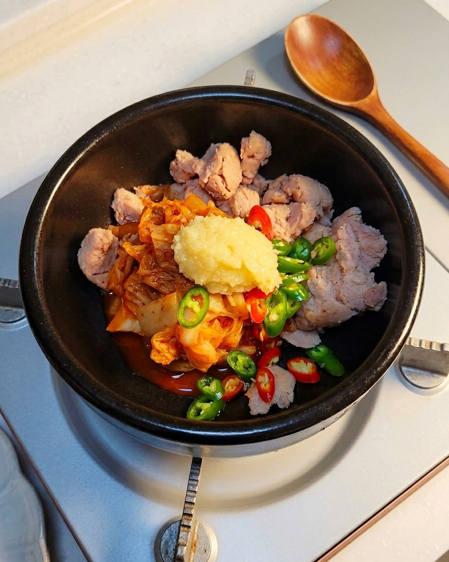 Un cucchiaio di aglio tritato aggiunto agli ingredienti nella pentola di pietra.
