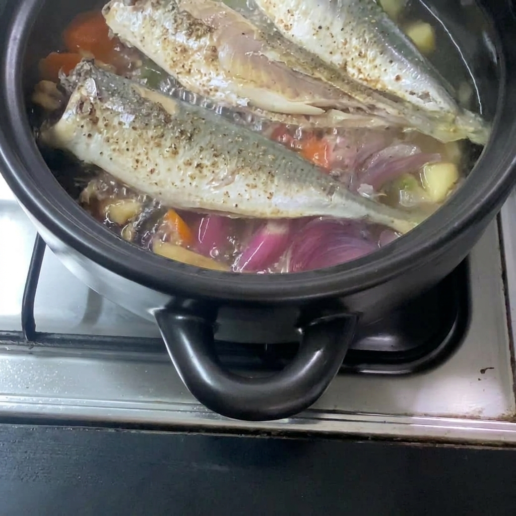 Il composto liquido di miso versato nel tegame, integrandosi con lo sgombro e le verdure cotte.