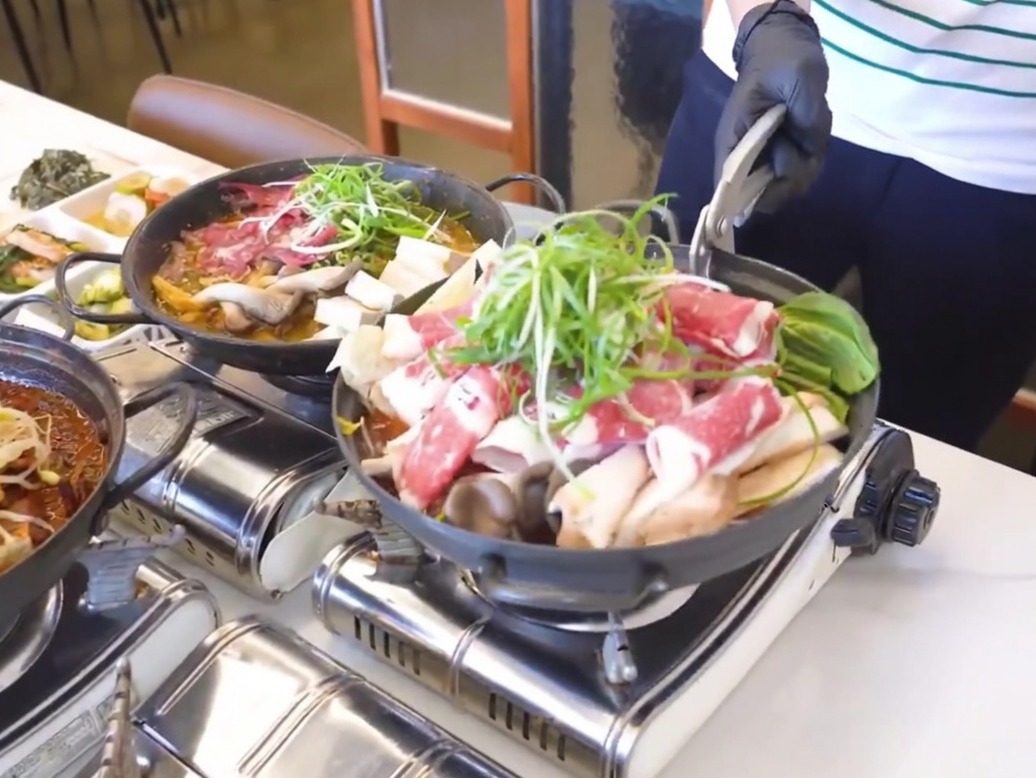 Una pentola di ghisa nera preparata con uno strato di ravanello cotto e kimchi sul fondo.