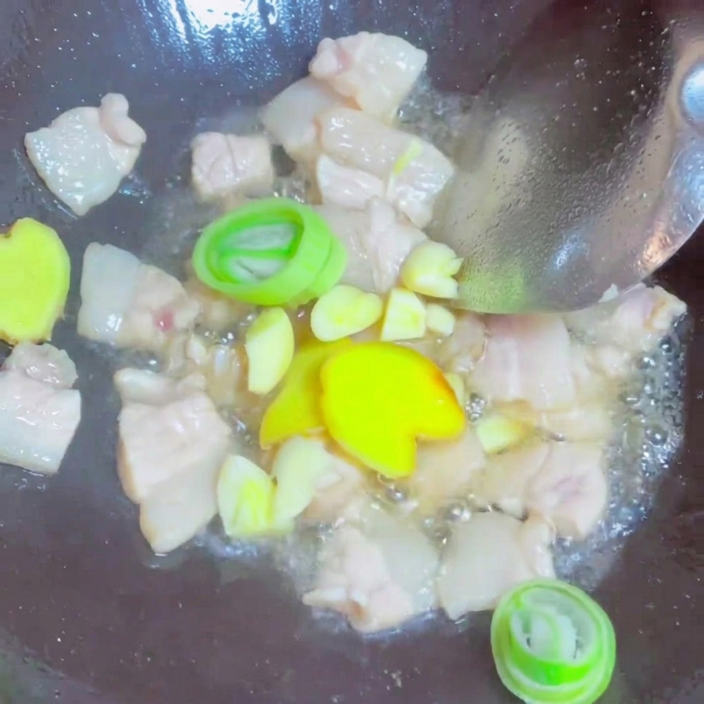 Fettine di zenzero fresco, aglio e rondelle di cipollotto verde saltate insieme ai pezzi di maiale nel wok.