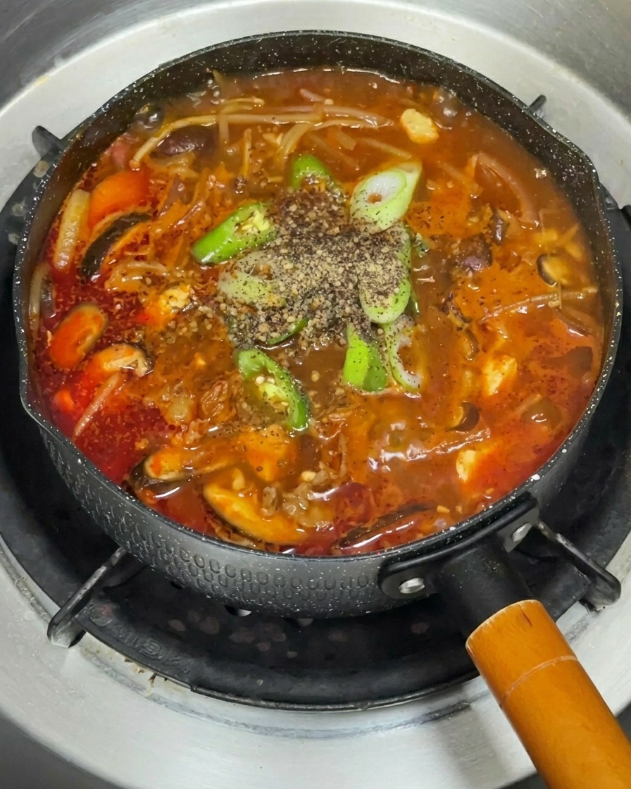Una varietà di verdure fresche, disposte ordinatamente, inclusi funghi, cipolla rossa e germogli di soia su un piatto.