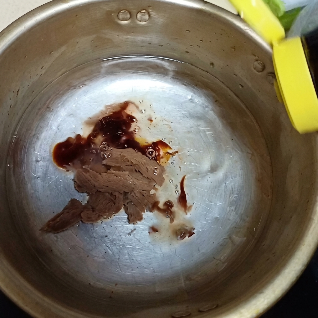 Salsa dostrica e un goccio di salsa di pesce versati nella pentola di metallo sopra la pasta di soia.