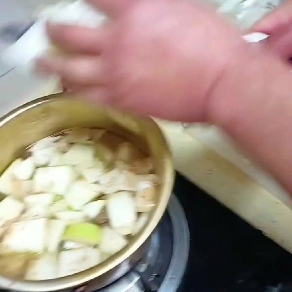 Foglie di cavolo cinese affettate poste in una pentola di zuppa a fuoco lento con altre verdure.