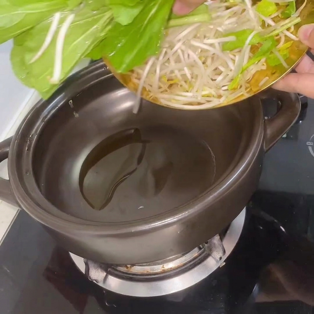 Bok choy fresco e germogli di soia mescolati nel tegame di terracotta riscaldato.