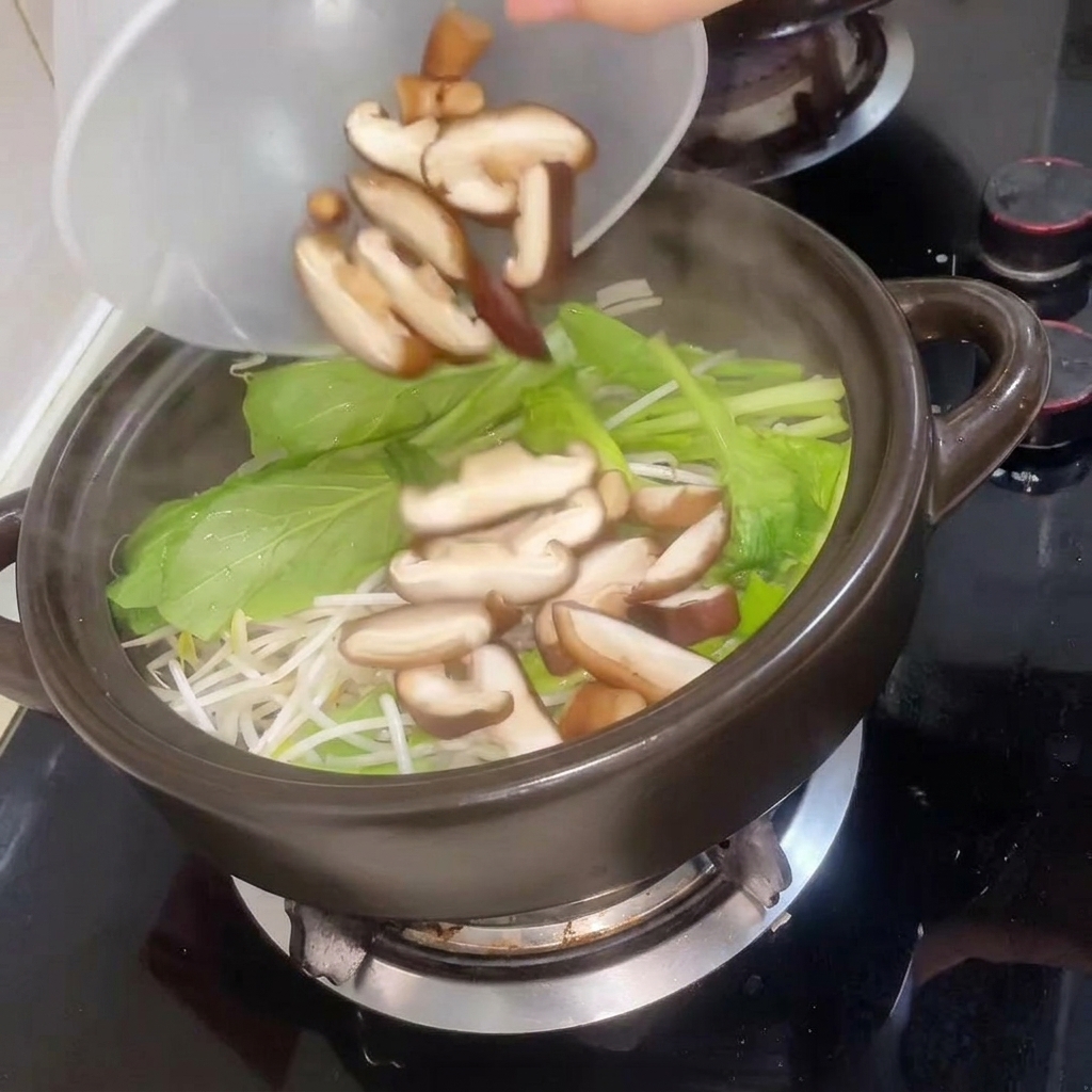 Funghi shiitake affettati aggiunti al tegame, seguiti dallacqua calda.