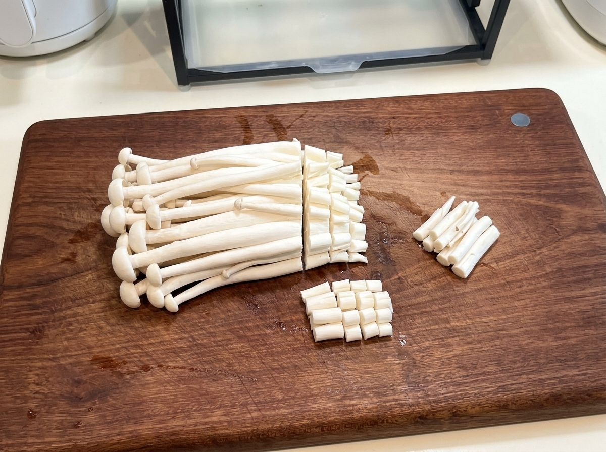 Funghi seafood freschi su un tagliere di legno mentre le radici vengono rimosse con un coltello.