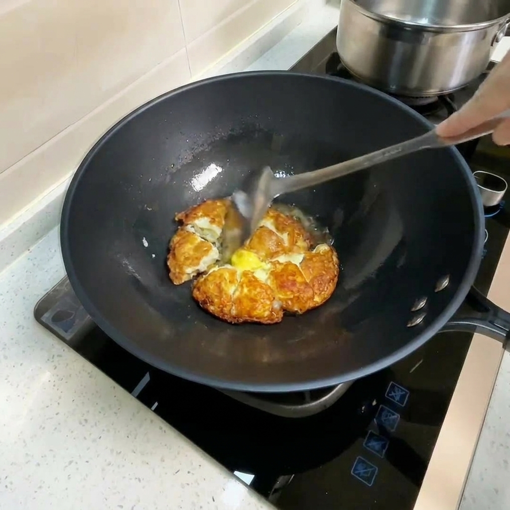 Acqua calda versata nel wok con uova fritte, che crea vapore.