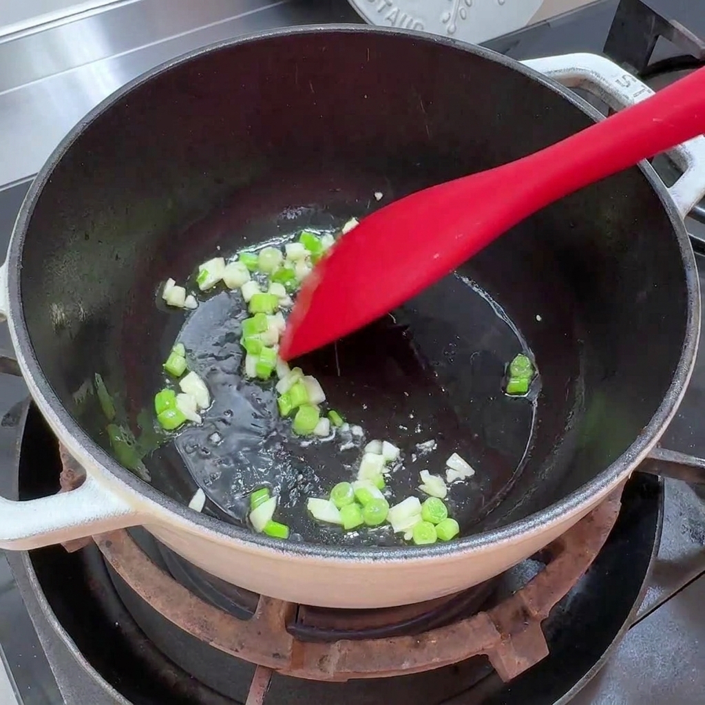 Cipollotti e aglio tritati che sfrigolano in una pentola con poco olio.