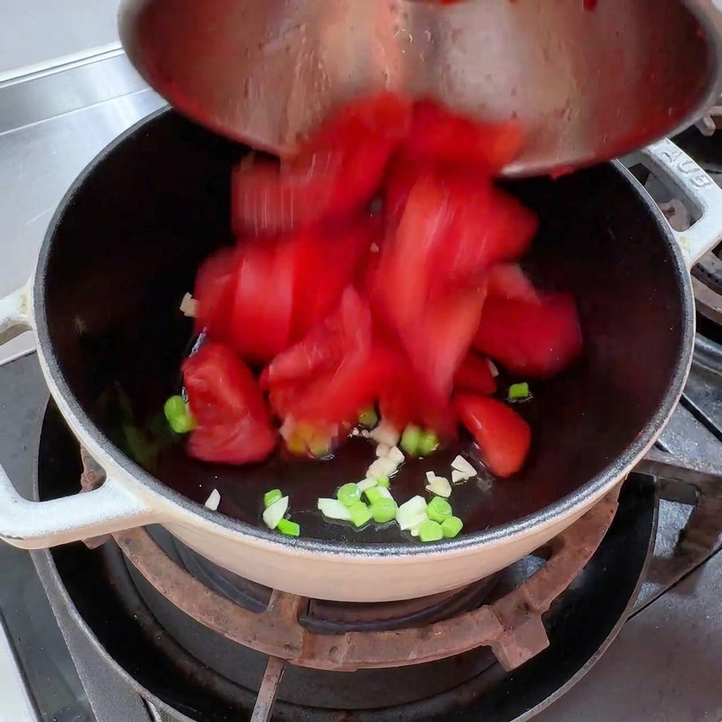 Pezzetti di pomodoro fresco sbucciato versati in una pentola.