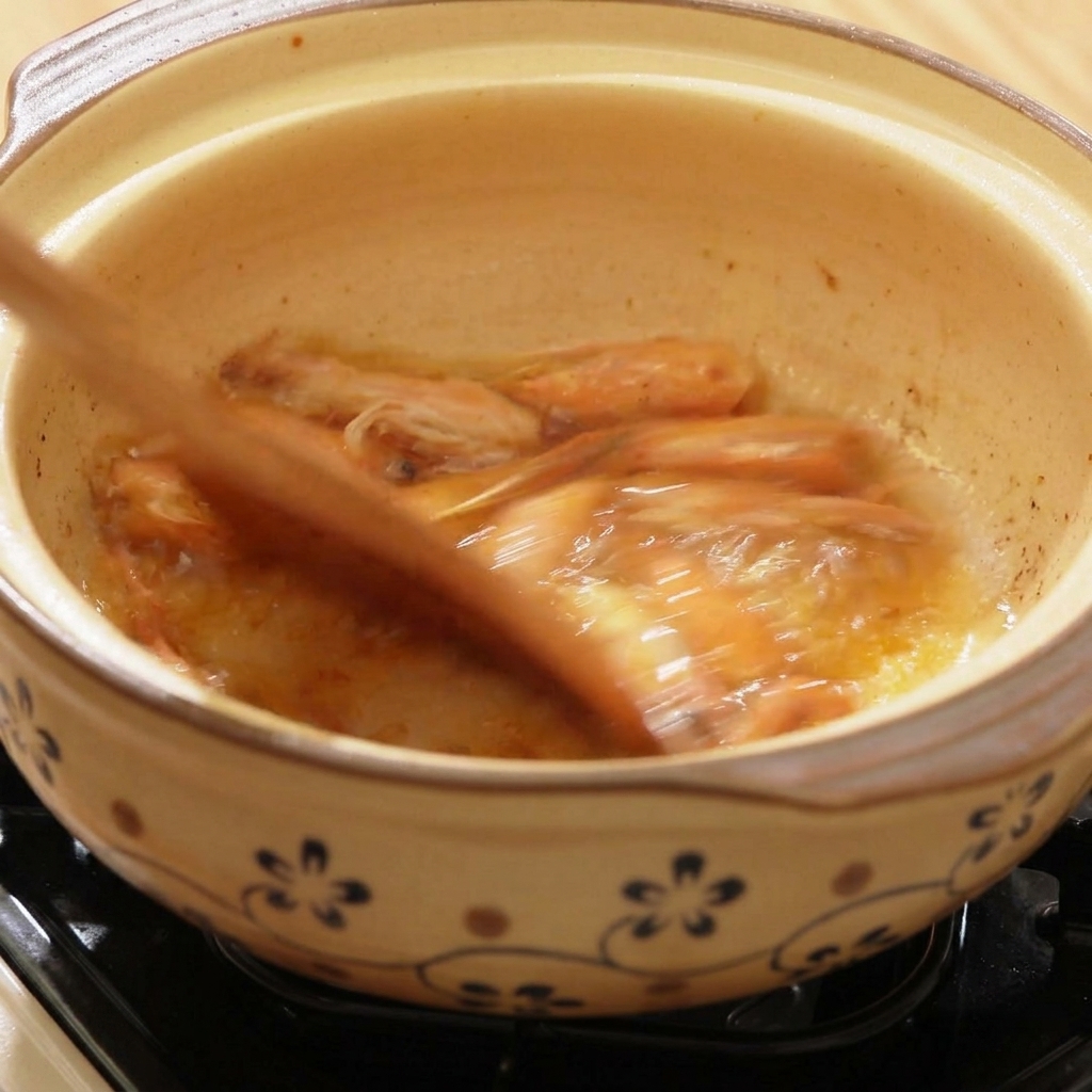 Acqua calda versata in un vaso di terracotta con teste di gambero saltate.