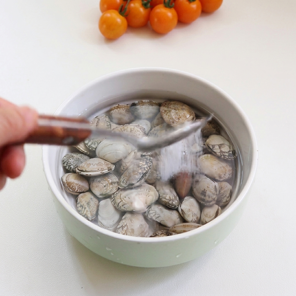 Vongole immerse in una ciotola dacqua con un cucchiaio di sale.