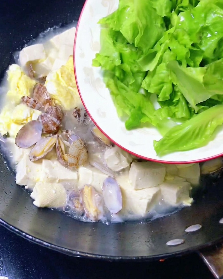 Foglie di lattuga fresca aggiunte alla zuppa pronta.