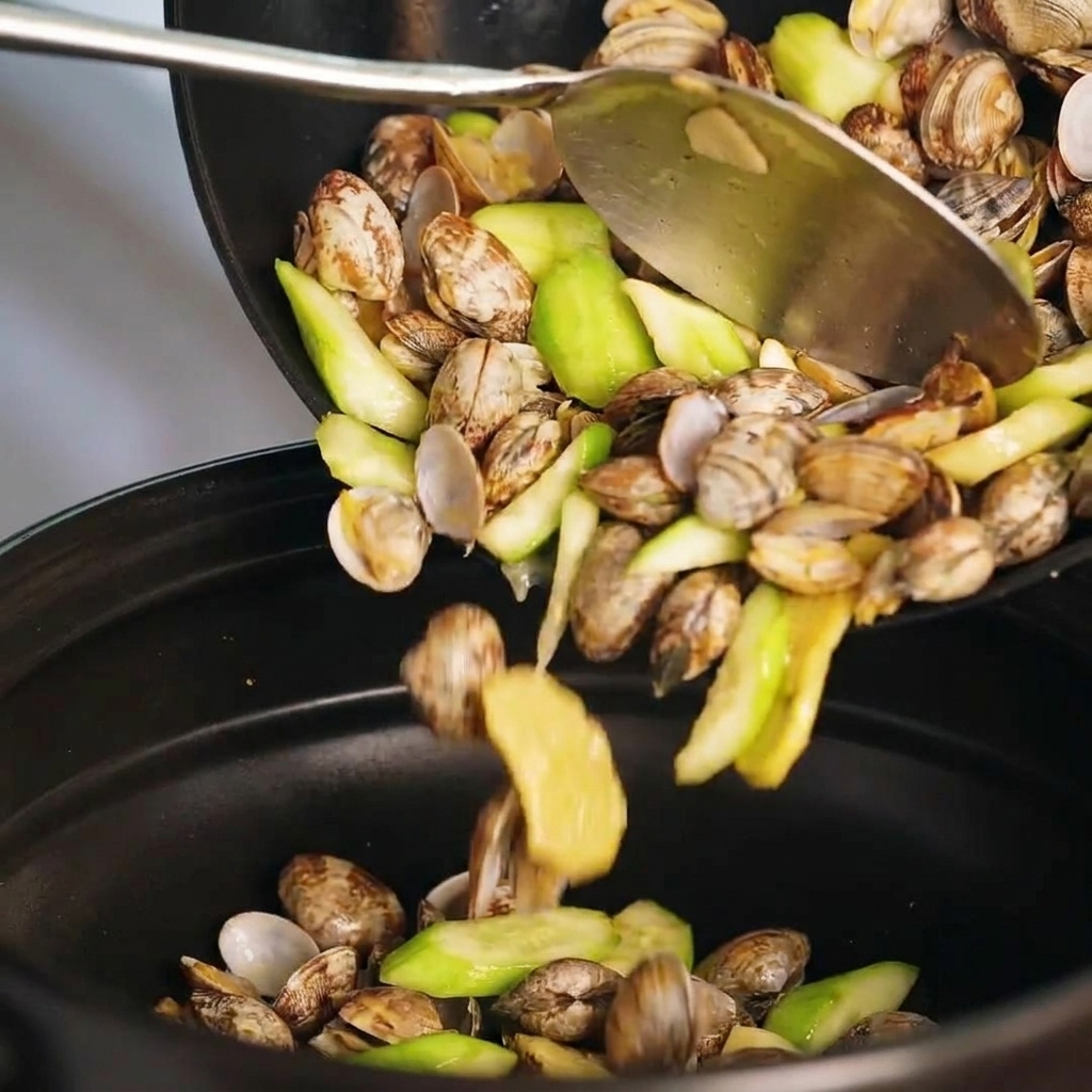 Il composto di vongole e luffa trasferito in una pentola di coccio.