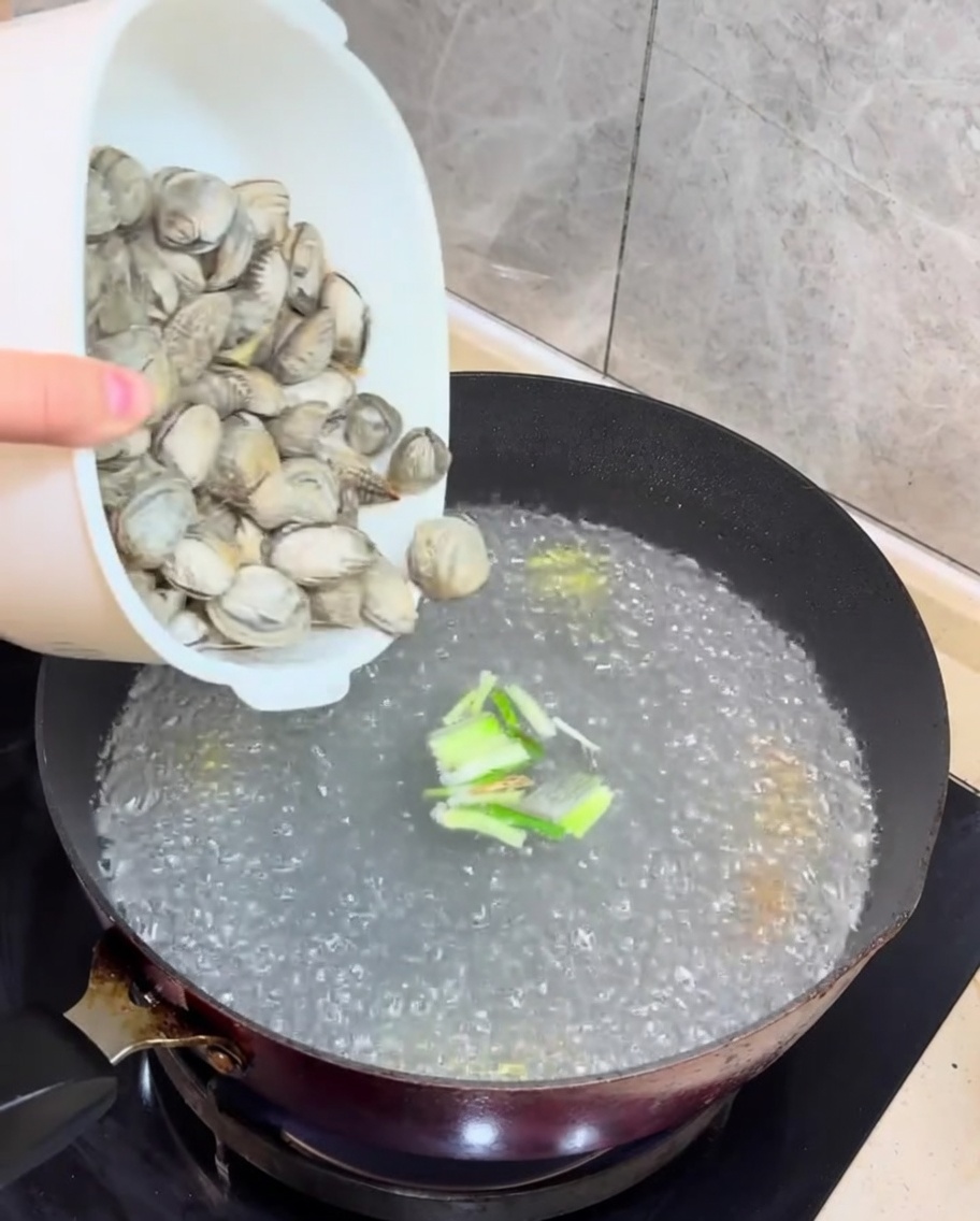 Vongole fresche e tofu a cubetti aggiunti al brodo bollente.