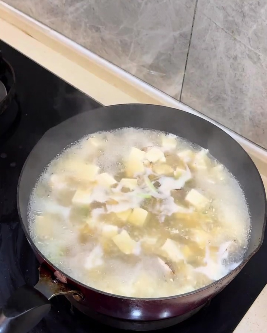 Verdi di cipollotto tritato aggiunti alla zuppa di vongole e tofu finita.