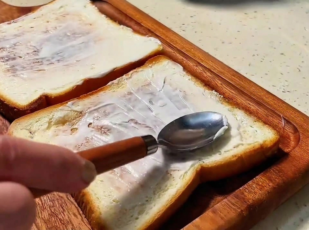 Due fette di pane tostato dorato spalmate con un velo di maionese.