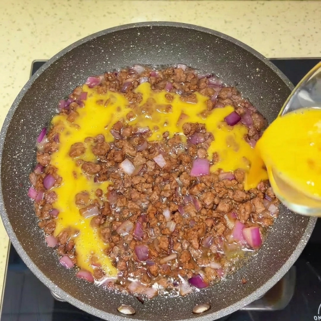 Carne macinata che viene sminuzzata in una padella calda con una spatola.