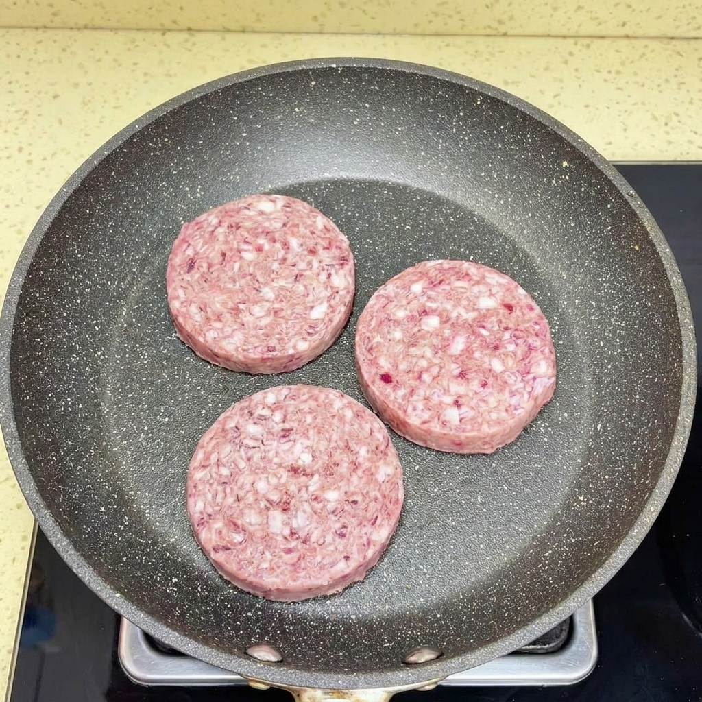 Carne macinata che viene sbriciolata e separata in una padella calda usando una spatola bianca.