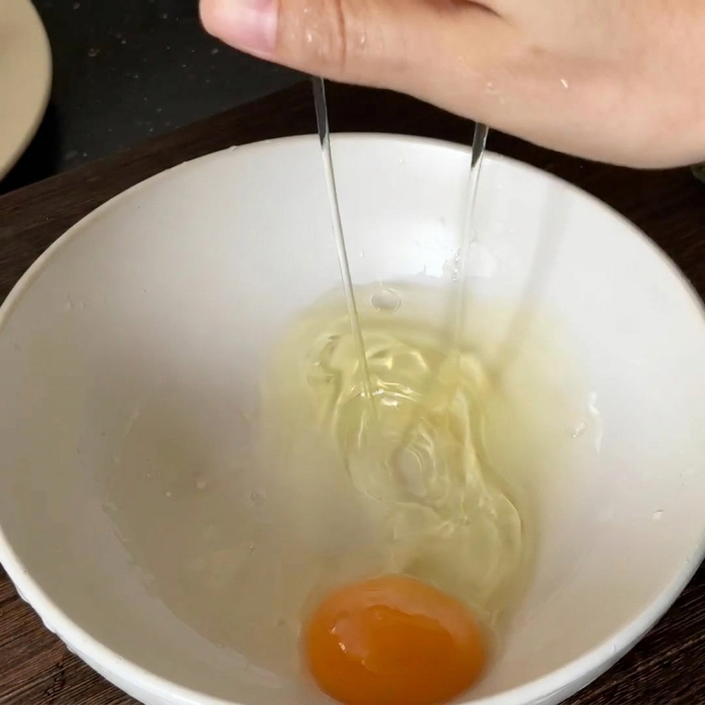 Un uovo fresco rotto in una ciotola bianca.