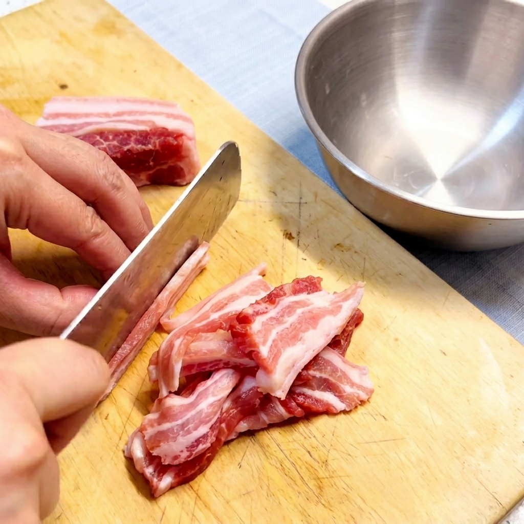 Fette di pancetta cruda disposte ordinatamente su un tagliere in legno.
