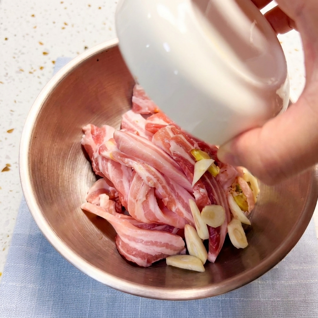Fette di pancetta che marinano in una ciotola di metallo con condimenti.