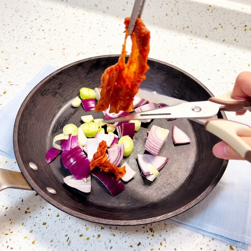 Kimchi tagliato con forbici da cucina direttamente nella padella.