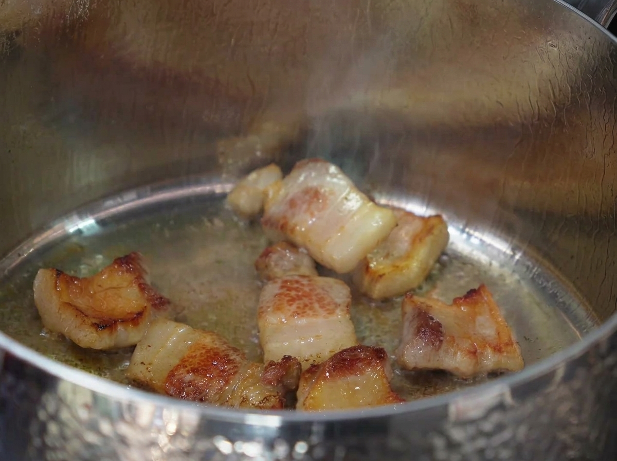 Aglio tritato mescolato nel grasso di pancetta sciolto e carne rosolata.