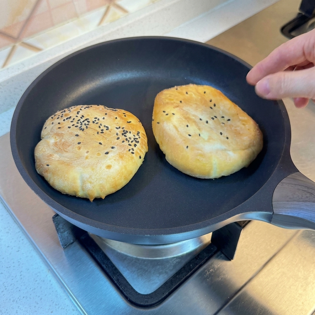 Panini in padella coperti con un coperchio, durante la cottura a vapore.